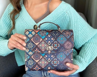 May include: A brown leather satchel with a colorful geometric pattern. The bag has a silver clasp and a top handle.