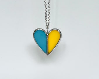 May include: A silver chain necklace with a heart-shaped pendant. The pendant is divided in half, with one side blue and the other side yellow.
