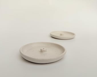 May include: Two white ceramic incense holders with a small hole in the center for burning incense cones. The holders have a speckled texture.