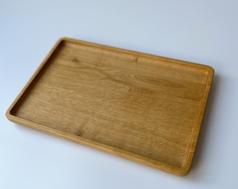 May include: A rectangular wooden tray with a light brown finish. The tray has a slightly raised edge and a smooth surface.