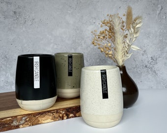 May include: Three ceramic candle jars with black labels that say "Irish Candle". The jars are in black, green, and white with speckled patterns. The jars are sitting on a wooden surface.