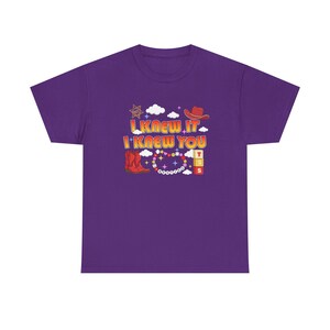 May include: A purple short-sleeve t-shirt featuring a graphic print with the text I KNEW IT I KNEW YOU. The design includes a red cowboy hat, red cowboy boots, a sheriff star, white clouds, colorful beads, and stacked blocks with the letters T S S.