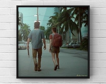 May include: Two people walk down a street lined with palm trees. The person in the front is wearing a red backpack and a blue shirt. The person in the back is wearing a blue shirt and carrying a gun. The street is empty except for a few parked cars.