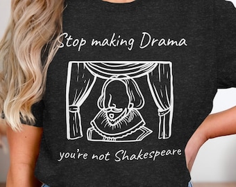 May include: A dark gray t-shirt with a white graphic of a person on a stage with the text "Stop making Drama you're not Shakespeare".