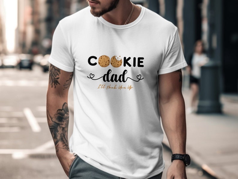 May include: White t-shirt with a graphic of two chocolate chip cookies and the text "Cookie Dad I'll hook you up".