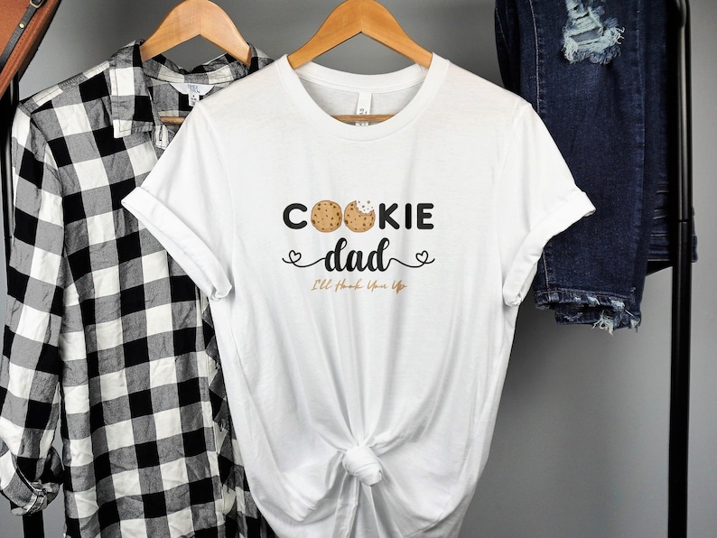 May include: White t-shirt with the text "Cookie Dad" and two chocolate chip cookies. The text below the cookies says "I'll love you forever".
