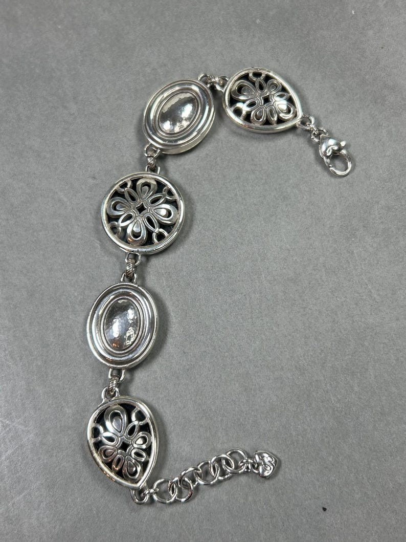 以下が含まれることがあります： 楕円形と円形の装飾的なリンクが特徴のシルバーカラーのブレスレット。 ブレスレットはロブスタークラスプ留め具で、透かし彫りのフローラルデザインが含まれています。 ブレスレットは光沢のある金属素材で作られています。