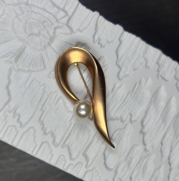Vintage gold-colored Op Art brooch with a large glass bead.