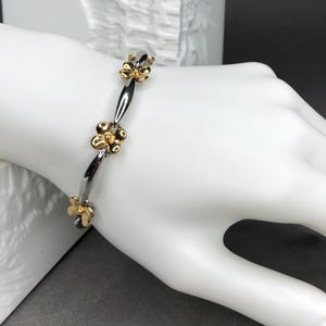 Silver-colored link bracelet/tennis bracelet with golden flowers.
