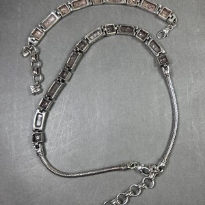 Peut inclure: Un ensemble collier et bracelet en argent. Le collier pr&eacute;sente des maillons rectangulaires avec un motif textur&eacute;, reli&eacute;s par une cha&icirc;ne souple. Le bracelet reprend le design avec un motif de maillons rectangulaires similaire et une fermeture &agrave; cha&icirc;ne.