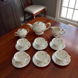 May include: A vintage tea set with a floral pattern. The set includes a teapot, creamer, sugar bowl, and six teacups and saucers.