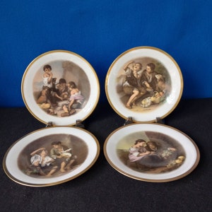 Puede incluir: Juego de cuatro platos decorativos con ilustraciones vintage de niños. Cada plato tiene un borde dorado y un fondo blanco con una ilustración marrón de niños jugando.