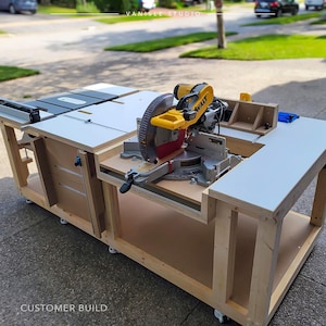 May include: A large wooden workbench featuring a yellow and black DeWalt mitre saw mounted on the surface. The workstation includes a white tabletop, integrated storage drawers, and caster wheels. The text VANISLE STUDIO and CUSTOMER BUILD appear.