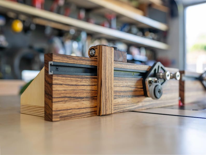 May include: A wooden woodworking jig with a dark wood grain finish. The jig features a sliding mechanism with metal tracks and adjustable components. The design includes a vertical support and a base, likely for precise cutting or shaping of wood.