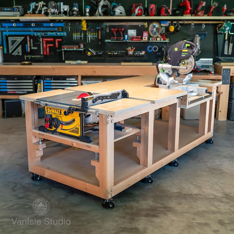 May include: A large wooden workbench on casters featuring a yellow DeWalt table saw integrated into the left side and a green and black Festool miter saw mounted on the right side. The workbench has a light wood finish and an open lower shelf.