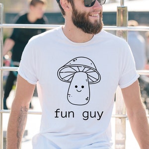 Könnte beinhalten: Weißes T-Shirt mit einer schwarzen Strichzeichnung eines lächelnden Pilzes und dem Text "fun guy".