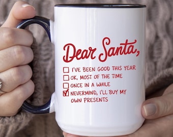 May include: White ceramic mug with a black rim and blue handle. The mug features the text "Dear Santa," in red script, along with a checklist of statements about behavior, with "Nevermind, I'll buy my own presents" checked.