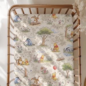 May include: A crib sheet featuring a repeating pattern of Winnie the Pooh characters including Tigger, Eeyore, Piglet, and Pooh Bear. The design includes trees, flowers, and bees in soft watercolor tones on a cream background, fitted on a wooden crib.