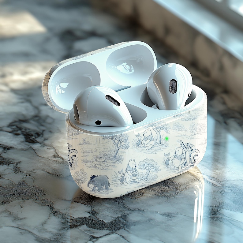 May include: White wireless earbuds in a charging case with a Winnie the Pooh design. The case is open, revealing the earbuds inside. The case has a blue and white toile pattern with illustrations of Winnie the Pooh and friends.