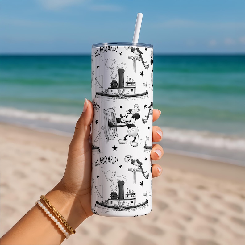 Puede incluir: Un vaso cil&iacute;ndrico blanco con un patr&oacute;n en blanco y negro que muestra un rat&oacute;n de dibujos animados al tim&oacute;n de un barco, un barco de vapor y el texto ALL ABOARD! intercalado con peque&ntilde;as estrellas. El vaso incluye tapa y pajita blanca.
