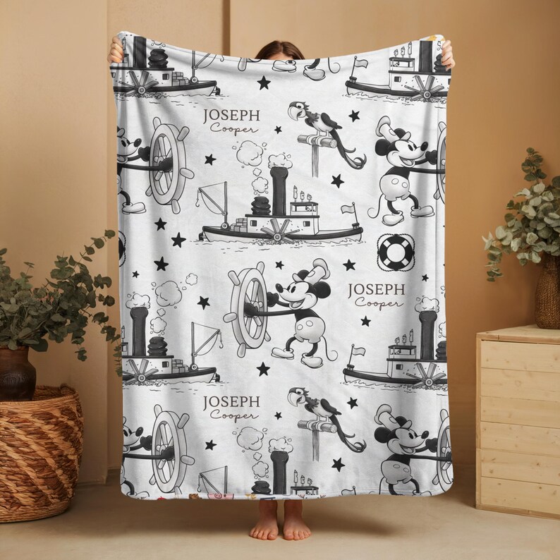 May include: A white fleece blanket featuring a repeating black and white pattern of a steamboat, a cartoon mouse steering a ship wheel, a parrot, and stars. The text "JOSEPH Cooper" is printed in a serif font throughout the design.