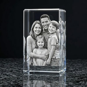 May include: A clear, rectangular crystal block featuring a black and white family portrait. The image shows a smiling family of four, with a father, mother, and two children. The crystal reflects light, creating a shimmering effect. A unique personalized gift.