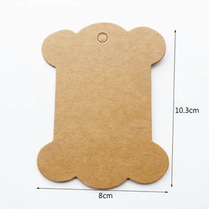May include: Brown paper spool tag with a hole at the top. The tag is 8 cm wide and 10.3 cm tall.