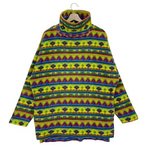 Op de afbeelding: Een kleurrijke trui met een hoge hals en een geometrisch patroon in tinten groen, blauw, rood en geel.