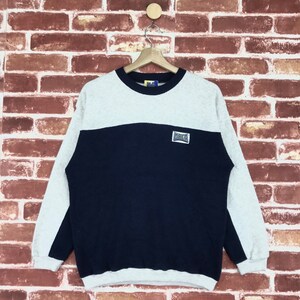 May include: A gray and navy blue sweatshirt with a white logo that says "DECA" on the front.