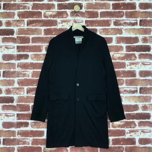 May include: A black long-sleeved jacket with a button closure and two pockets. The jacket has a stand-up collar and is made of a soft, comfortable fabric.
