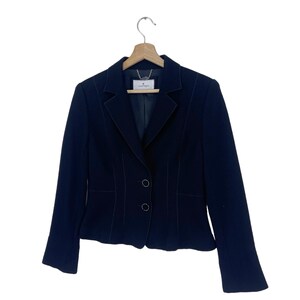 K&ouml;nnte beinhalten: Ein schwarzer Blazer mit einer figurbetonten Silhouette und einem einzigen Knopfverschluss. Der Blazer hat einen Schalkragen und lange &Auml;rmel.