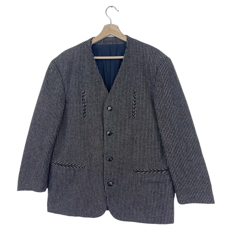 May include: A black and white striped blazer with a V-neck and button closure. The blazer has decorative stitching on the front and pockets.