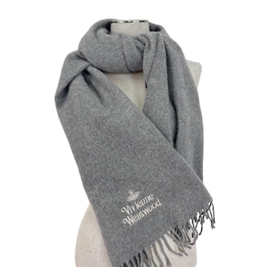 May include: Gray wool scarf with a fringe. The scarf has the text "Vivienne Westwood" embroidered on it in white.