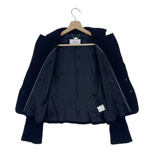 K&ouml;nnte beinhalten: Ein schwarzer Blazer mit wei&szlig;em Futter und einem kleinen wei&szlig;en Etikett mit dem Text "Couture" im Inneren.