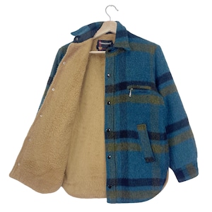 Op de afbeelding: Een blauw en groen geruit flanellen shirt met een bruine fleecevoering. Het shirt heeft een knoopsluiting aan de voorkant en een enkele borstzak.