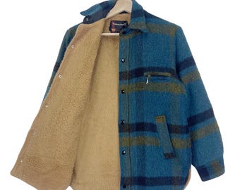 May include: A blue and green plaid flannel shirt with a brown fleece lining. The shirt has a button-up front and a single chest pocket.
