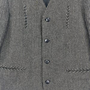 May include: A black and white striped blazer with a v-neck and five black buttons. The blazer has two pockets on the bottom and decorative stitching on the front.