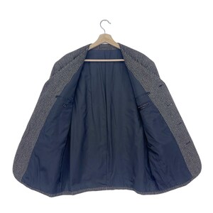 May include: A gray and white striped blazer with a black lining. The blazer is unbuttoned and the lining is visible.