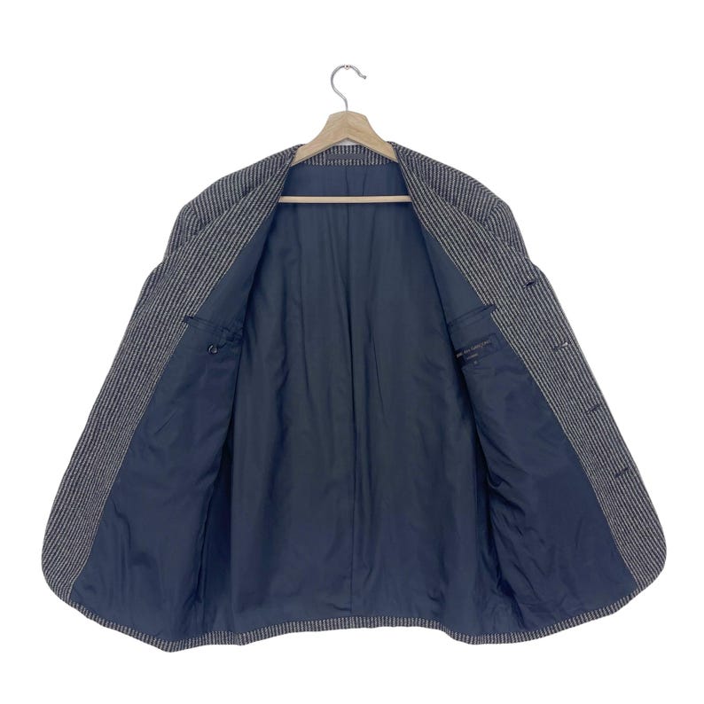 May include: A gray and white striped blazer with a black lining. The blazer is unbuttoned and the lining is visible.