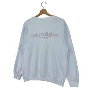 Puede incluir: Una sudadera azul claro con un logotipo "Courr&egrave;ges Paris" multicolor en la espalda.