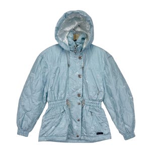 K&ouml;nnte beinhalten: Eine hellblaue Kapuzenjacke mit Kordelzug in der Taille und Knopfverschluss. Die Jacke hat ein dezentes Muster und einen silbernen Rei&szlig;verschluss.