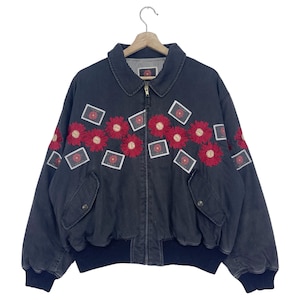 Peut inclure: Une veste bomber noire avec une fermeture éclair et des fleurs brodées rouges. La veste a deux poches sur le devant et une ceinture côtelée.