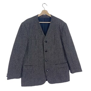 May include: A black and white striped blazer with a button-up front and black embroidered details. The blazer has a v-neck and a single button closure.