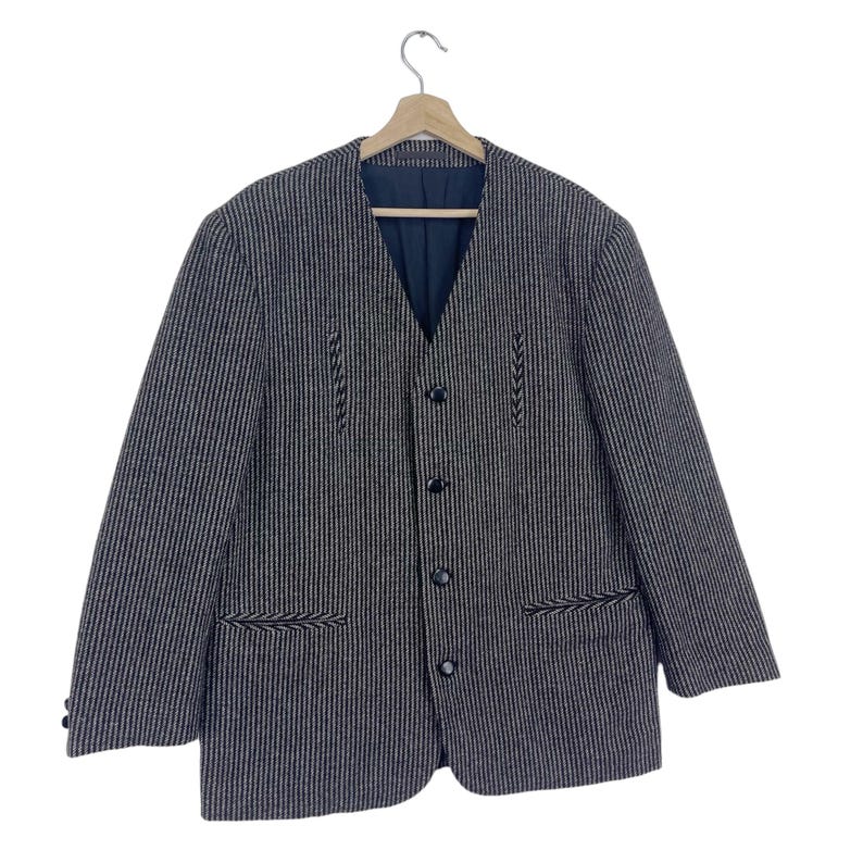 May include: A black and white striped blazer with a button-up front and black embroidered details. The blazer has a v-neck and a single button closure.