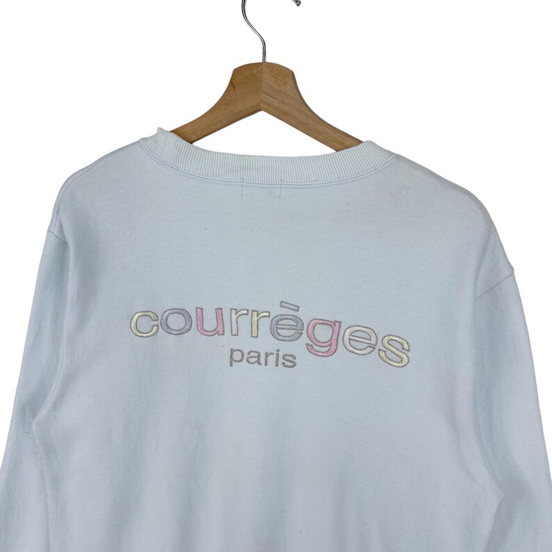 Puede incluir: Una sudadera azul claro con un logotipo bordado multicolor que dice "Courr&egrave;ges Paris".