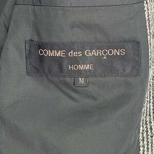May include: Black label with white text reading "COMME des GAR&Ccedil;ONS" and "HOMME" with a size "M" label below.