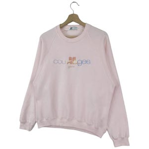 K&ouml;nnte beinhalten: Ein rosa Sweatshirt mit einem bunten "Courr&egrave;ges Paris" Logo auf der Vorderseite.
