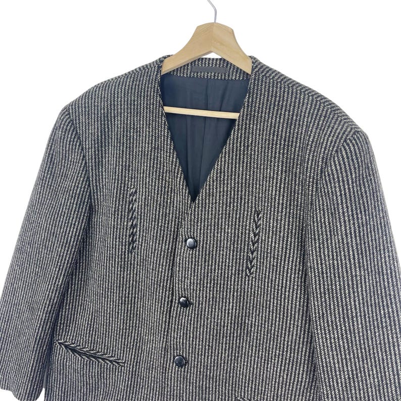 May include: A black and white striped blazer with a button-up front and a v-neck. The blazer has a textured fabric and a subtle pattern.