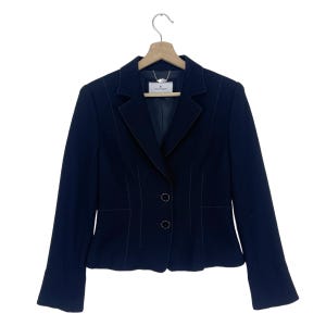 K&ouml;nnte beinhalten: Ein schwarzer Blazer mit einem einzigen Knopfverschluss und einem kleinen Etikett mit der Aufschrift "Valentino" auf der Innenseite.