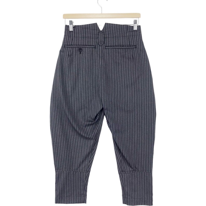 May include: Black and white striped pants with a high waist and a wide leg. The pants have a V-shaped waistband and a button closure.